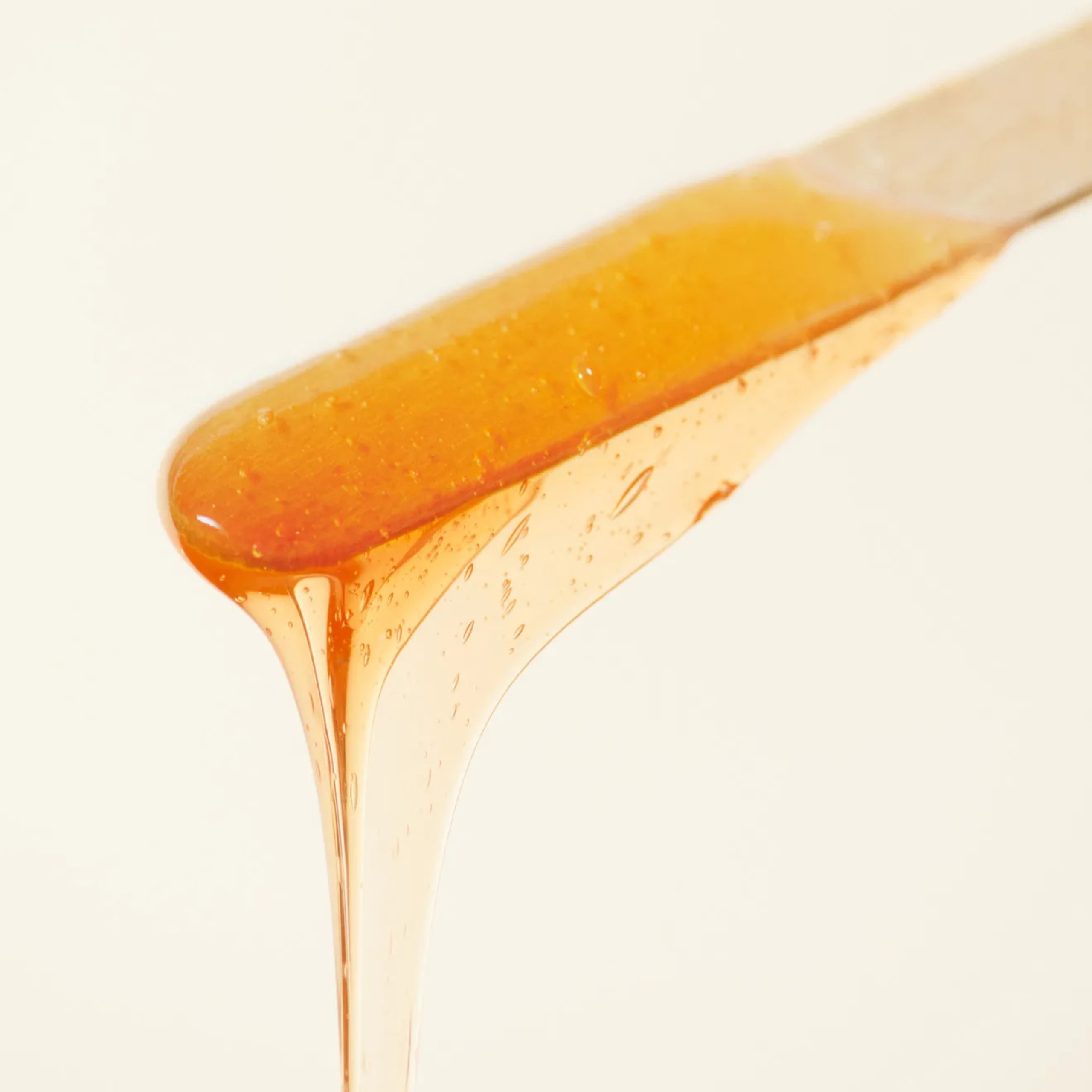 การแว็กซ์กำจัดขนขาด้วยแว็กซ์ร้อน/แว็กซ์น้ำตาล โดยมีผู้เชี่ยวชาญกำลังทาแว็กซ์บนผิวด้วยไม้พาย